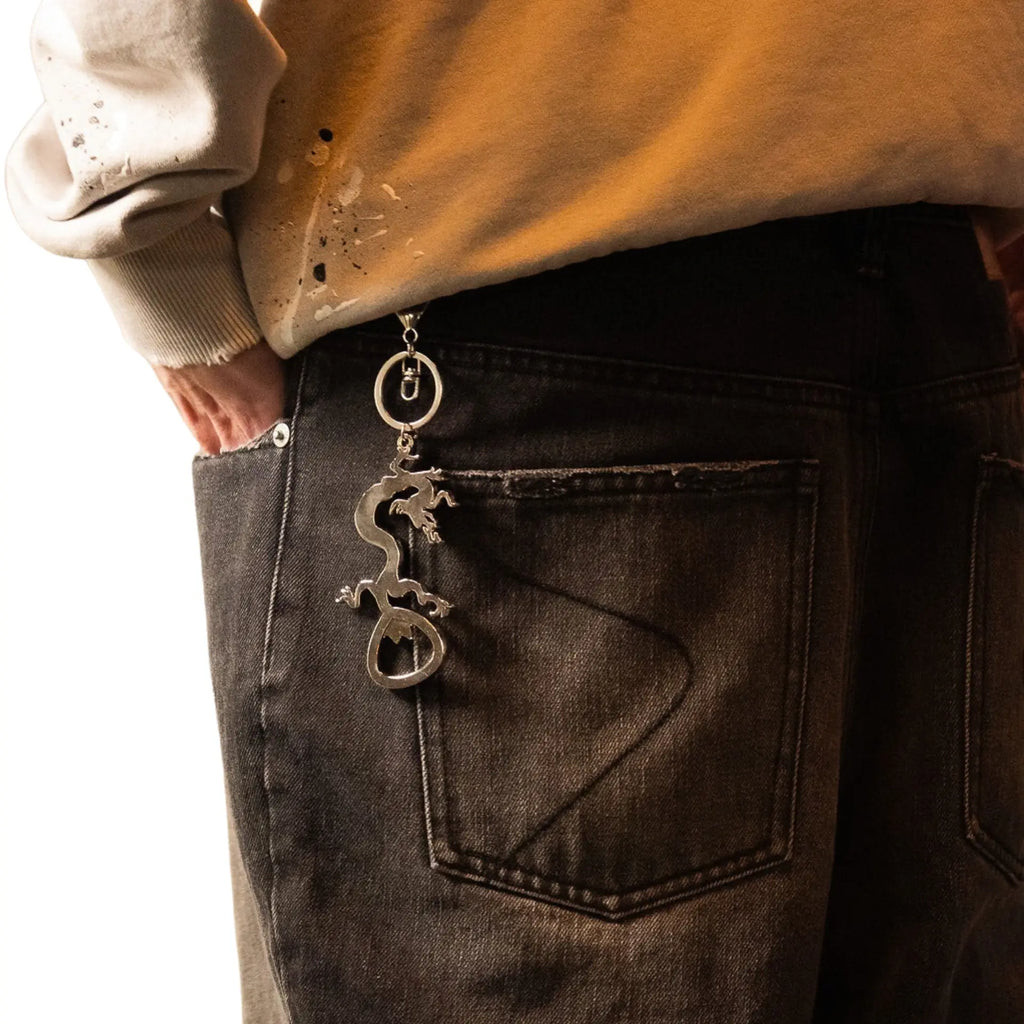 Dragon bottle opener clipped to black jeans